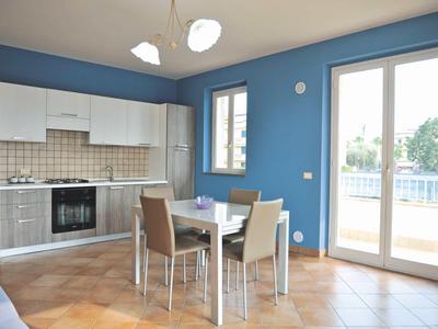 Cocina y comedor modernos con paredes azules, suelo de baldosas claras y ventana grande.