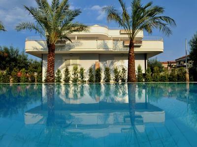 Modern hotel building with pool and palm trees under blue sky