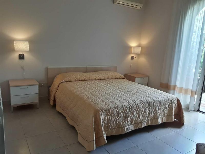 Camera d'hotel luminosa con letto grande e comodini su entrambi i lati.