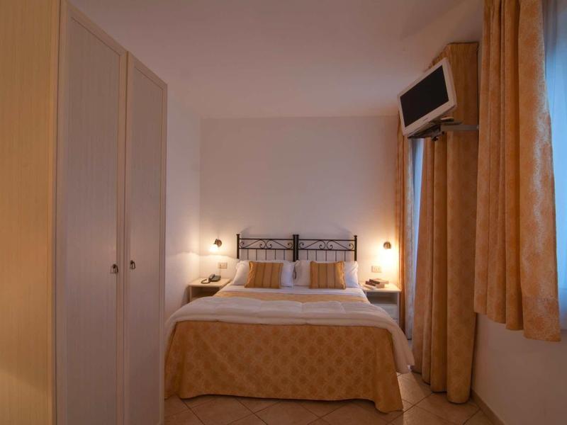 Camera d'albergo accogliente con letto matrimoniale, lampade da comodino e TV a muro.