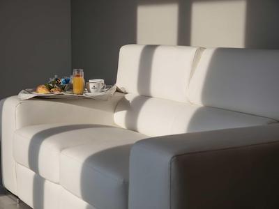 Hellgraues Sofa mit Schattenstreifen, auf dem ein Tablett mit Frühstück steht.