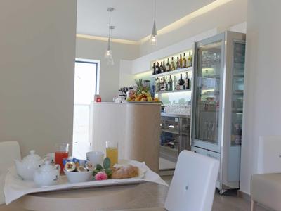 Moderner Café-Innenraum mit weißem Mobiliar, Getränkeauswahl und hellem Tageslicht.