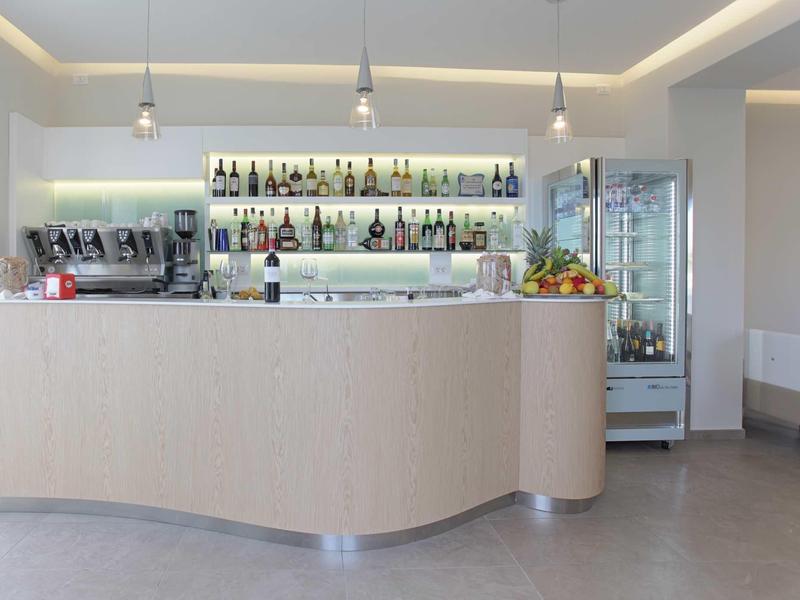 Moderner Barbereich mit hellem Holz, Getränkeregale, Kühlschrank und minimalistischer Beleuchtung.