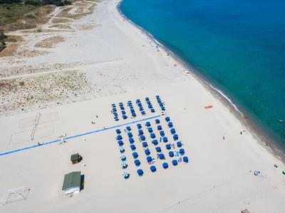 Spiaggia di sabbia bianca con lettini blu e acqua turchese.
