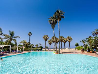 Grande piscina con palme e cielo blu limpido in un resort alberghiero.