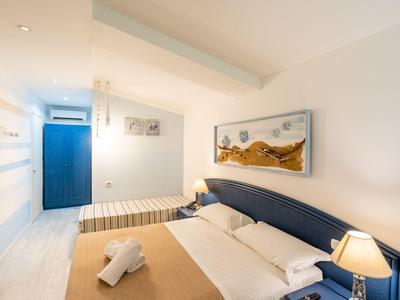 Camera d'albergo luminosa con letto matrimoniale, poltrona e arredi moderni in toni caldi.