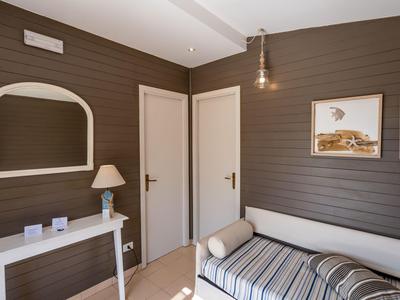 Piccola stanza d'hotel con divano letto, pavimenti in legno chiaro e pannelli murali marroni.