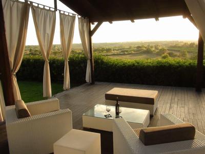 Zastřešená terasa s pohodlným posezením a výhledem na zelenou krajinu při západu slunce.