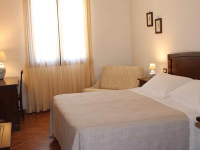 Przytulny pokój hotelowy z podwójnym łóżkiem, biurkiem i wygodnym krzesłem w świetle dziennym.