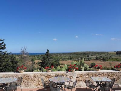 Taras z stołami i krzesłami z widokiem na rozległy krajobraz i błękitne niebo.