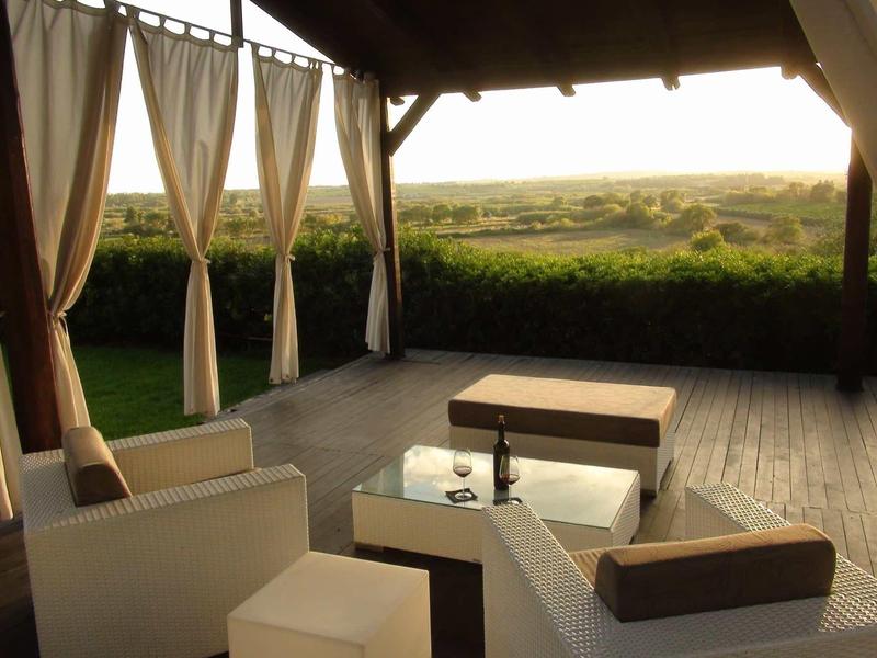 Przytulny kącik wypoczynkowy pod pawilonem z widokiem na zielony krajobraz o zachodzie słońca.