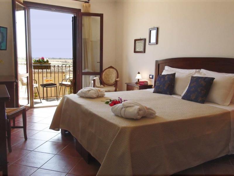 Jasny pokój hotelowy z podwójnym łóżkiem, dwoma szlafrokami i balkonem z widokiem na morze.