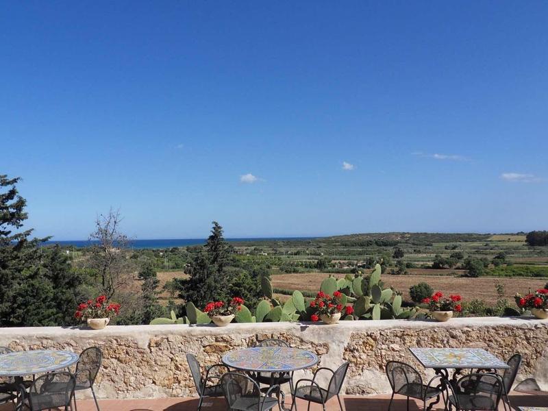 Taras z stołami i krzesłami z widokiem na rozległy krajobraz i błękitne niebo.