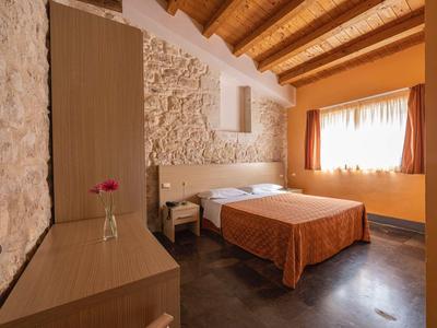 Gemütliches Hotelzimmer mit Doppelbett, Holzmöbeln und warmen Farben.