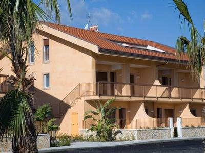 Meerdere verdiepingen tellend hotelgebouw met balkons en palmbomen op een zonnige dag.