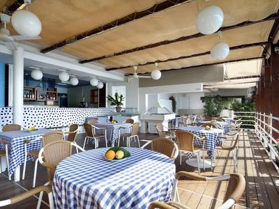 Restaurace na terase s kostkovanými ubrusy a dřevěným nábytkem pod pergolou