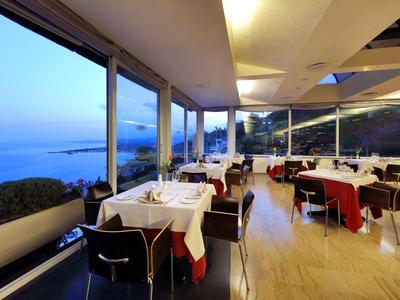 Moderní restaurace s terasou a výhledem na moře při soumraku.