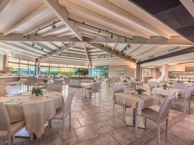 Světlá, moderní jídelna se prostřenými stoly a dřevěným stropem s trámy v hotelu.