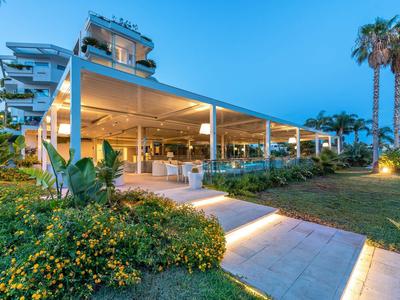 Oświetlona restauracja na świeżym powietrzu z nowoczesną architekturą i ogrodem o zmierzchu.