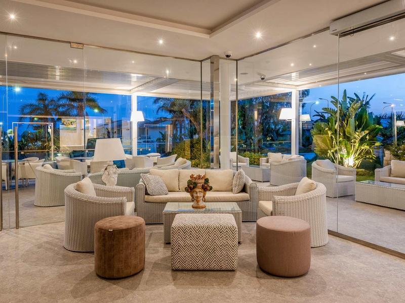 Moderní lounge s posezením a rostlinami v hotelu za soumraku.