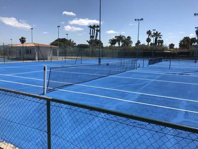 Campo da tennis blu con tempo soleggiato, rete e recinzione in primo piano