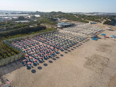 Kilometrowa piaszczysta plaża z uporządkowanymi rzędami parasoli i leżaków.