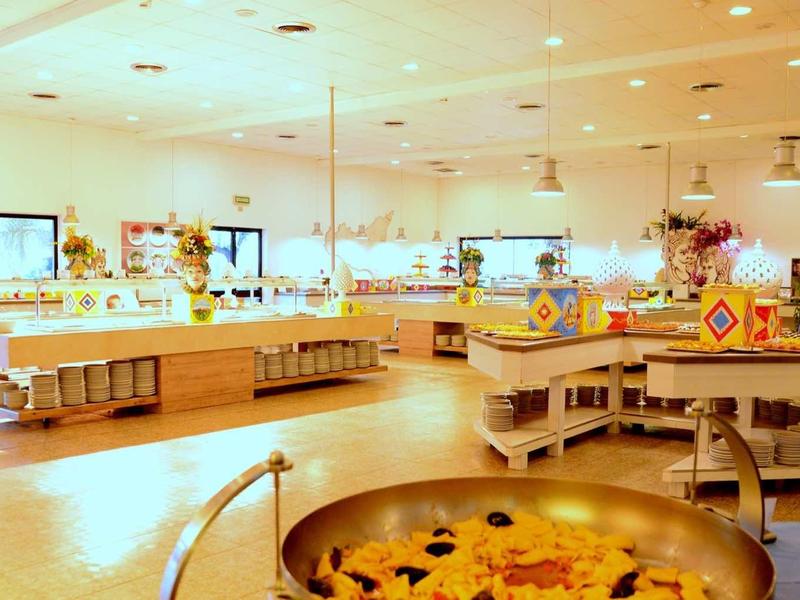 Jasna, nowoczesna restauracja bufetowa z okrągłymi wyspami kuchennymi i różnorodnymi potrawami.