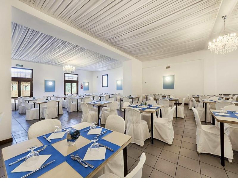 Elegancka jadalnia z białymi nakryciami stołów i niebieskimi akcentami w hotelu.