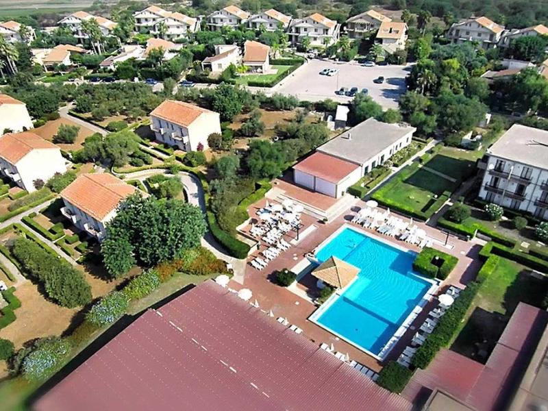 Widok z lotu ptaka na hotel z kilkoma budynkami i prostokątnym basenem w centrum.