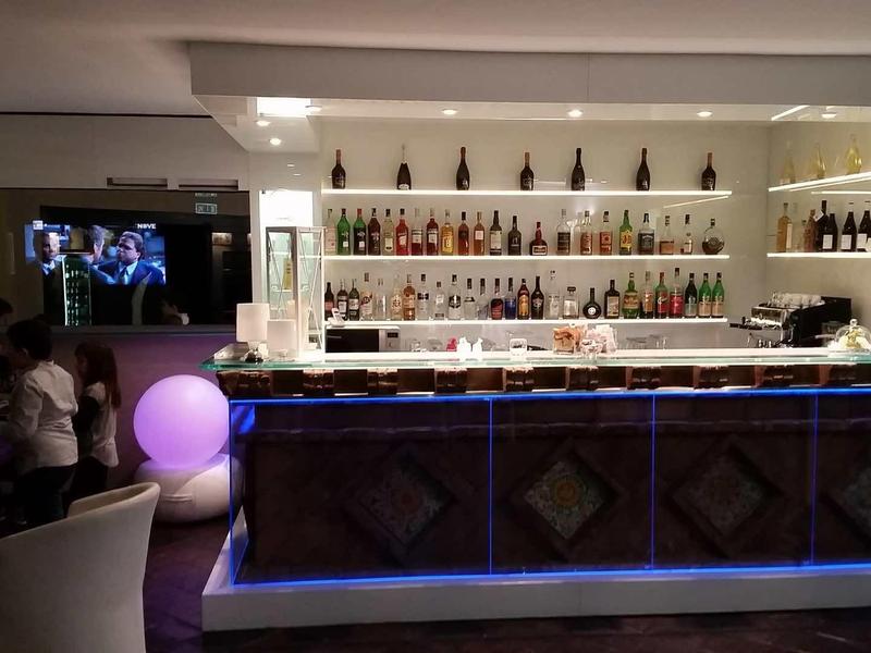 Nowoczesny bar hotelowy z podświetlanym kontuarem i półkami z butelkami w tle