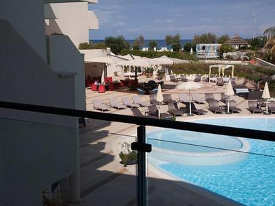 Vue depuis le balcon sur une piscine avec transats et parasols dans un hôtel.
