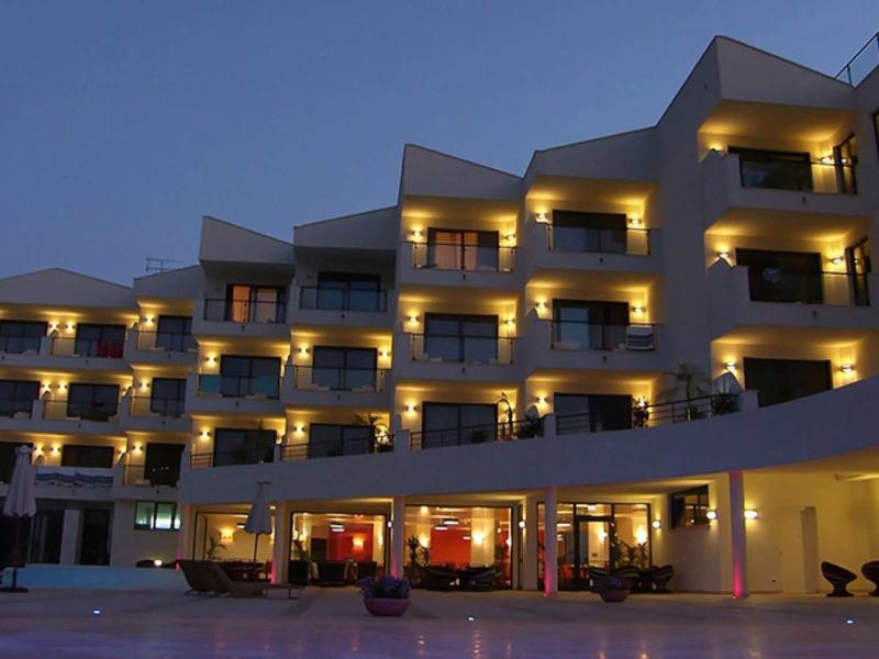 Bâtiment d'hôtel à plusieurs étages avec balcons éclairés au crépuscule.