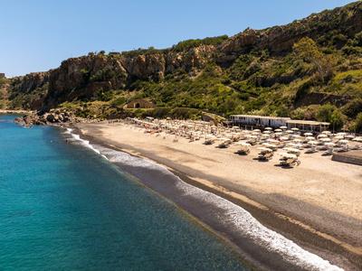 Piaszczysta plaża z parasolami i wzgórzami w tle pod bezchmurnym niebem