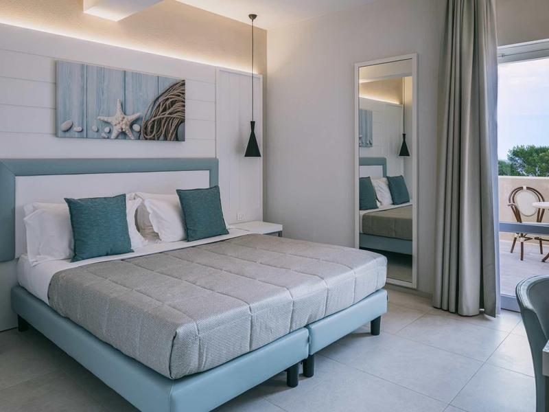 Modern hotel room with double bed and balcony access with a view.