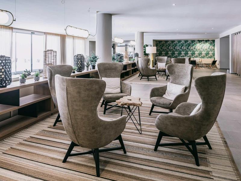 Moderner, heller Wartebereich mit beigen Sesseln, Teppich und großen Fenstern für viel Tageslicht.