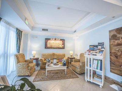 Salon lumineux avec fauteuils confortables, table et œuvres murales dans un hôtel.