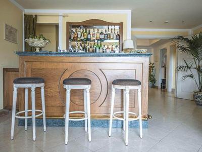 Bar avec trois tabourets en bois et étagères avec des bouteilles en arrière-plan dans une pièce lumineuse