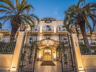 Illuminated hotel entrance with gate and palm trees at dusk.