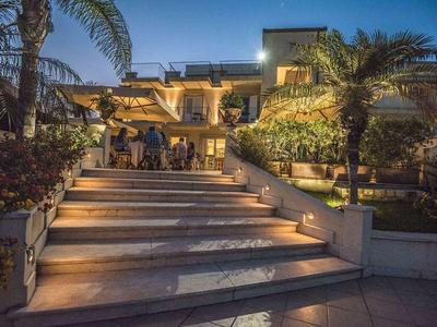 Illuminated staircase leads to a modern, multi-story hotel with palm trees and guests.