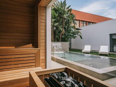 Moderní sauna s dřevěným obložením s výhledem na venkovní bazén a lehátka.