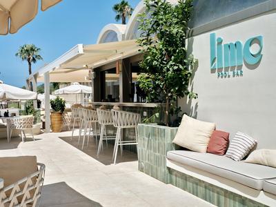 Stylová hotelová terasa s posezením a slunečníky pod jasnou modrou oblohou.