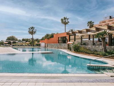 Moderní venkovní bazén s lehátky a palmami v slunném hotelovém resortu.