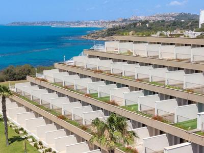 Hotelové terasy s výhledem na modré moře a pobřeží za jasné oblohy.