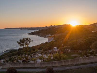 Západ slunce nad pobřežím s kopci a klidným mořem