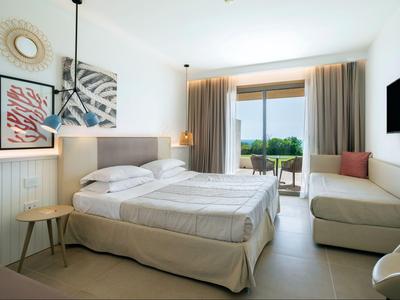 Světý hotelový pokoj s manželskou postelí, pohovkou, balkonem a moderním zařízením.