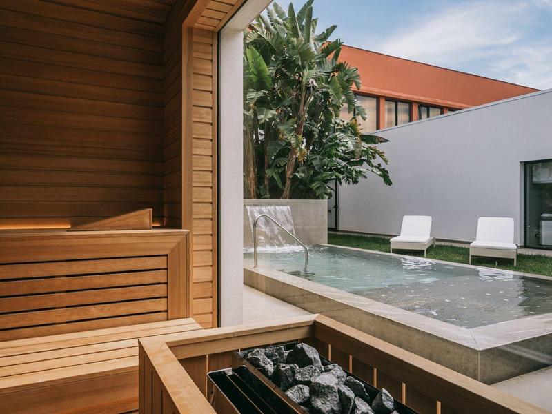 Moderní sauna s dřevěným obložením s výhledem na venkovní bazén a lehátka.