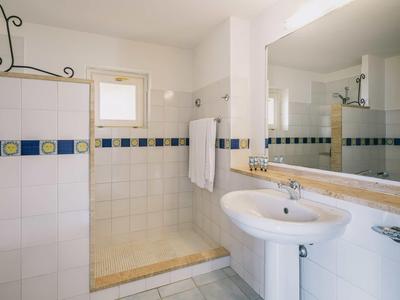 Lichte badkamer met inloopdouche, wastafel en grote spiegelwand.