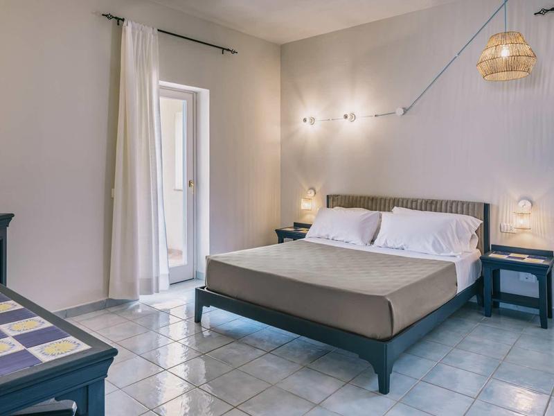 Modern hotelkamer met tweepersoonsbed, betegelde vloer en natuurlijk licht.