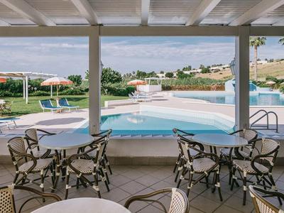 Bazén s lehátky a stoly pod zastřešenou oblastí v rekreačním středisku.