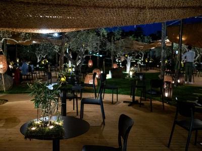 Příjemný venkovní bar s stoly, židlemi a náladovým osvětlením v noci